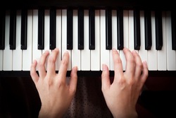 Closeup woman's hand playing piano. Favorite classical music. Top view with dark vignette.