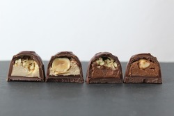 chocolate corus candies in section with a white chocolate filling with hazelnuts peanuts praline ganache on a gray background with space for text and copyspace. Day chocolate sweets without diet.