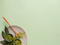 matcha tea on grey plate with spoon and leaf on grean background. Concept healthy drink, copyspace, flatlay, top view
