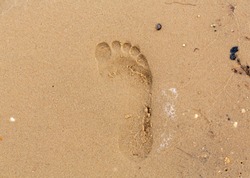 Imprint of the foot of a child in heavy sand in the summertime.