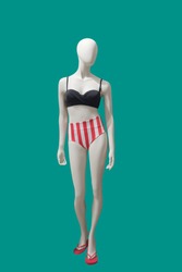 Full-length female mannequin wearing fashionable swimsuit, isolated on green background. No brand names or copyright objects.