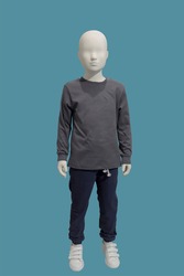 Full length image of a child display mannequin dressed in brown sweater and blue jeans isolated on a blue background.
