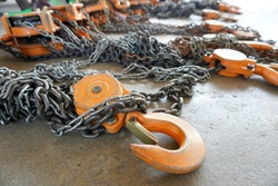 Orange color Industrial hook with chains or chain hoist on concrete floor to wait for the Monthly inspection which is a condition of use of the industrial factory, Department of oil and gas production