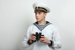 Young sailor holds binoculars in hands on a white background