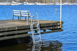 bench and ladder on wooden jetty over lake in Sweden