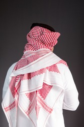 Saudi Arabian man wears traditional Saudi Clothes (Shmag). Photograph portrait from behind.