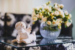 beautiful ceramic figurine of an angel on the table on the background of the hotel room