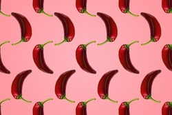 Pattern of red peppers isolated on pink background. Creative photo of peppers aligned with copy space.