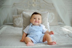 little child baby boy.Cute boy sitting on the white blanket at the bed.Little baby boy