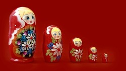 Set of closed nesting dolls on red background. Bigger and smaller similar wooden toys.