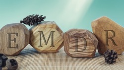 Letters EMDR written on wooden irregular blocks. Eye Movement Desensitization and Reprocessing psychotherapy treatment concept.