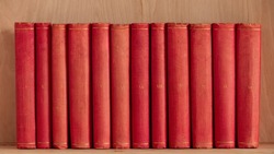 Twelve red antique book volumes in row. Roman numerals on hardback book spine. Old books banner.
