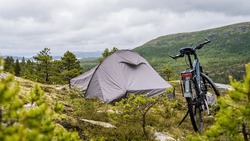 Tent and bike surrounded by green natural environment in a typical norwegian landscape