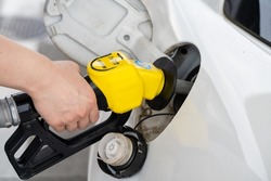 A hand to refuel a car with high-octane gasoline.