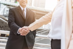 businessman and woman handshake outdoor in city with sunlight. Business greeting or agreement concept.
