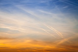 Beautiful sky at sunset, streaked airplane traces. Contrast between warm and cold colors Concept for environmental protection