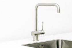 Close up of a worktop of a modern kitchen and the steel sink and water tap.