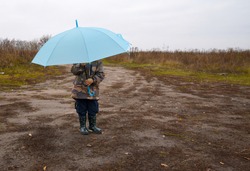 a small child stands under an umbrella. the child hid behind an umbrella