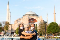 Portrait of happy tourist family in mask in front of Hagia Sophia Mosque Istanbul, Turkey. Tourism back to Turkey after covid-19 lockdown. Cute mother, father, daughter, son travel together.