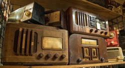 A variety of vintage table top radios grouped together on a shelf indoors closeup view