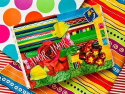 A vibrant colorful scrapbook with a collage (fish, flowers, grass, stripes, geometric ornaments, and cut-out words Amor and May) shot on the background of bright striped wrapping paper.