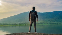 Young man standing near the lake and mountain and enjoying view of nature