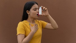 Asthmatic patient catching inhaler having an asthma attack. Young woman having asthma, chronic obstructive pulmonary disease