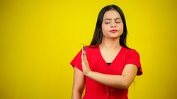 Portrait of a Asian beautiful young woman unhappy or confident standing say no, studio shot isolated yellow background, Indian female pose saying reject gesture with copy space