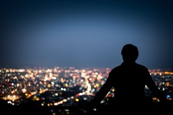 Silhouette of man looking above the city in the night