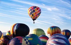 A rising hot-air balloon while others are still on the ground, competition concept. leading. leadership. Concept of The First Place. First balloon rising above others.