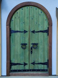 Wooden double barn door with rounded corners. Wooden plank door with forged metal parts. 