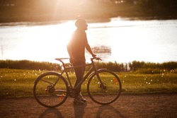 young man rides a Bicycle, enjoying nature and sun. A free traveler travels with a bicycle at sunset. concept of adventure and travel. lonely cyclist resting in park.