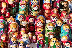 Brightly painted population of wooden Matryoshka or Babuska stacking dolls. Varying sizes. Females faces with red lipstick and rosy cheeks. Girls in traditional floral dresses and scarfs