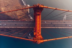 Aerial view of Golden Gate Bridge in foggy visibility during evening time, metropolitan transportation  infrastructure, birds eye view of automotive car vehicles on road of suspension construction 