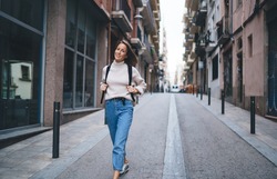 Portrait of happy Caucasian woman with backpack walking around touristic city and exploring streets architecture, carefree female traveller 30s visiting town during international vacations