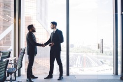 Multiracial male employees in formal clothing doing handshake during business meeting in office enterprise for find solutions negotiations, proud ceo found merger agreement of acquisition on deal