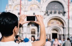 Cropped female tourist using cellphone camera for photographing ancient architecture buildings during summer vacations in Venice, woman shooting travel video vlog on modern smartphone technology