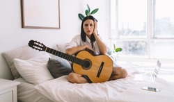 Worried brunette female is sad that she can't play guitar. Young woman can’t do hobby with musical instrument because of headache. Bad mood, depression and apathy