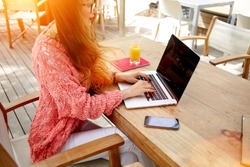 Cropped image of a female keyboarding on laptop computer with copy space screen while sitting in cafe outdoors, young attractive woman working on net-book during morning breakfast in coffee shop 