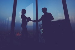 Silhouette of businessman shaking hands in honor of the transaction with his new woman partner, male and female entrepreneurs congratulate each other with their successful work