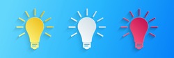 Paper cut Light bulb with rays shine icon isolated on blue background. Energy and idea symbol. Lamp electric. Paper art style. Vector.