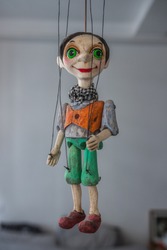 String operated puppet (marionette) from Prague (Czech Republic). Beautiful close up of this strange looking tiny person. It is hanging in the air. Wearing a scarf, short hair, has big green eyes.