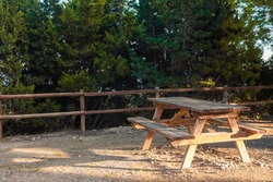 Beautiful picnic area. Wooden table with sun rays giving contrast. Peaceful greenery.