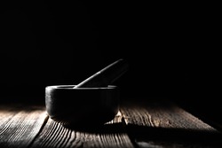 Stone mortar with pestle on black background