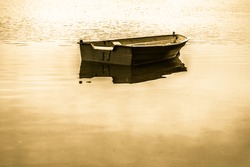 Vintage photo of old boat for fishing on the lake, quiet surface of water. Nature background, vintage effect.
