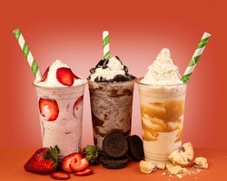 Three glasses of colorful milkshake cocktails - chocolate, strawberry and vanilla decorated with fresh strawberries and mint isolated on colorful background