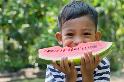 Asian Child Enjoy Eating The Watermelon.