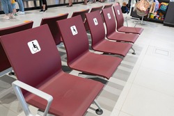 A row of burgundy chairs with a disabled sign at the airport.