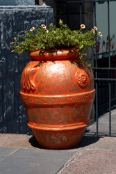 Large orange vase with tsfet on the sidewalk of the city.