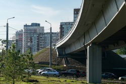Concrete car overpass in the city center. Busy car traffic under the overpass. Concrete overpass with massive concrete supports.